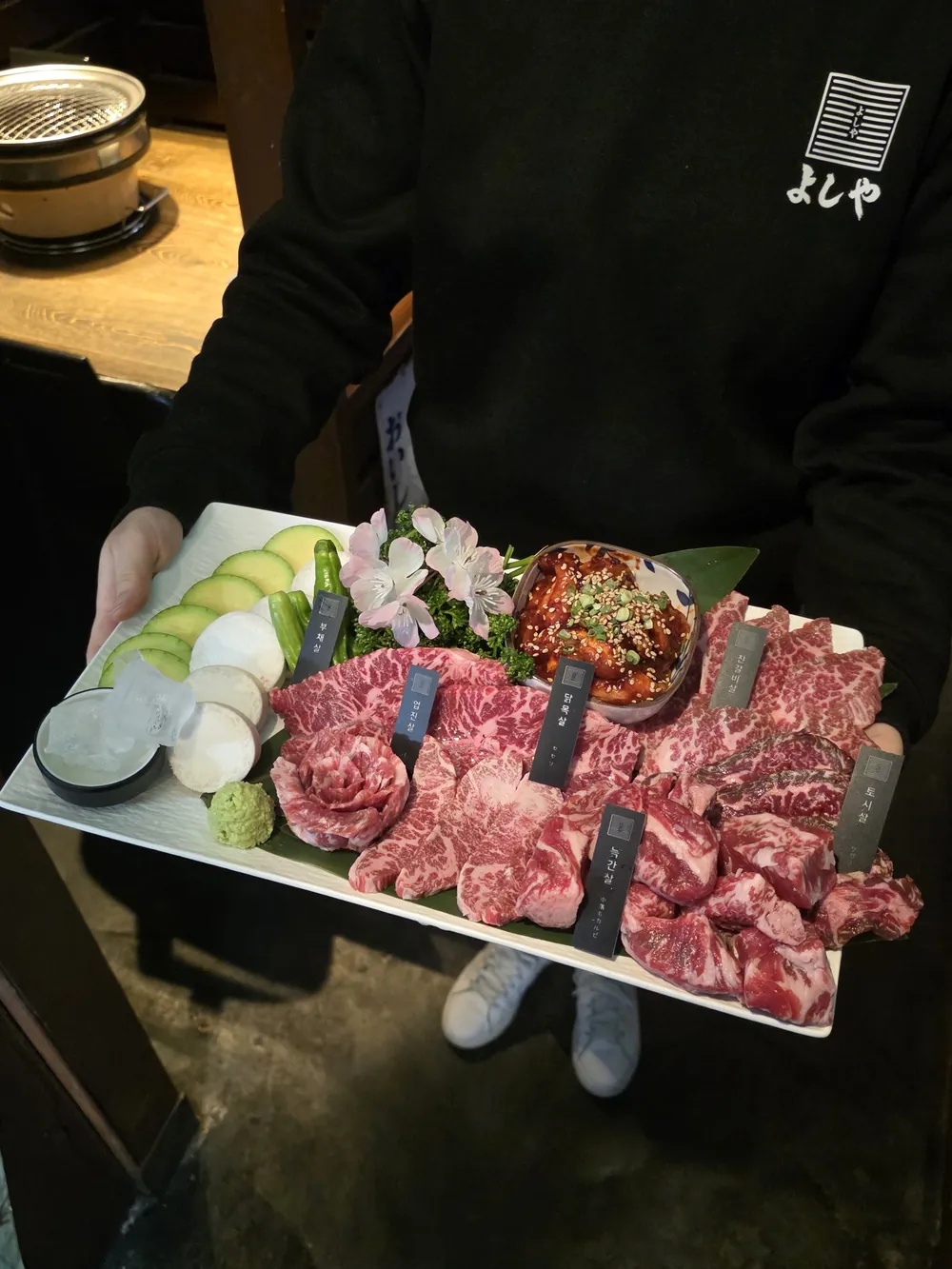 요시야 앞치마를 두른 직원이 들고 있는 고기 플레이트